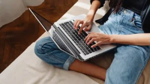 Woman browsing the web for cheap flights using the best travel websites, with a laptop on her lap.