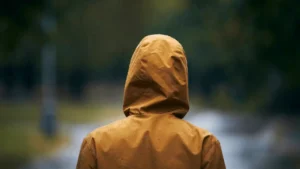 Back view of hiker with a yellow hiking jacket and the hood drawn up.