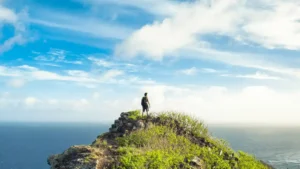 Men solo hiking on top of a mountain overlooking the ocean.