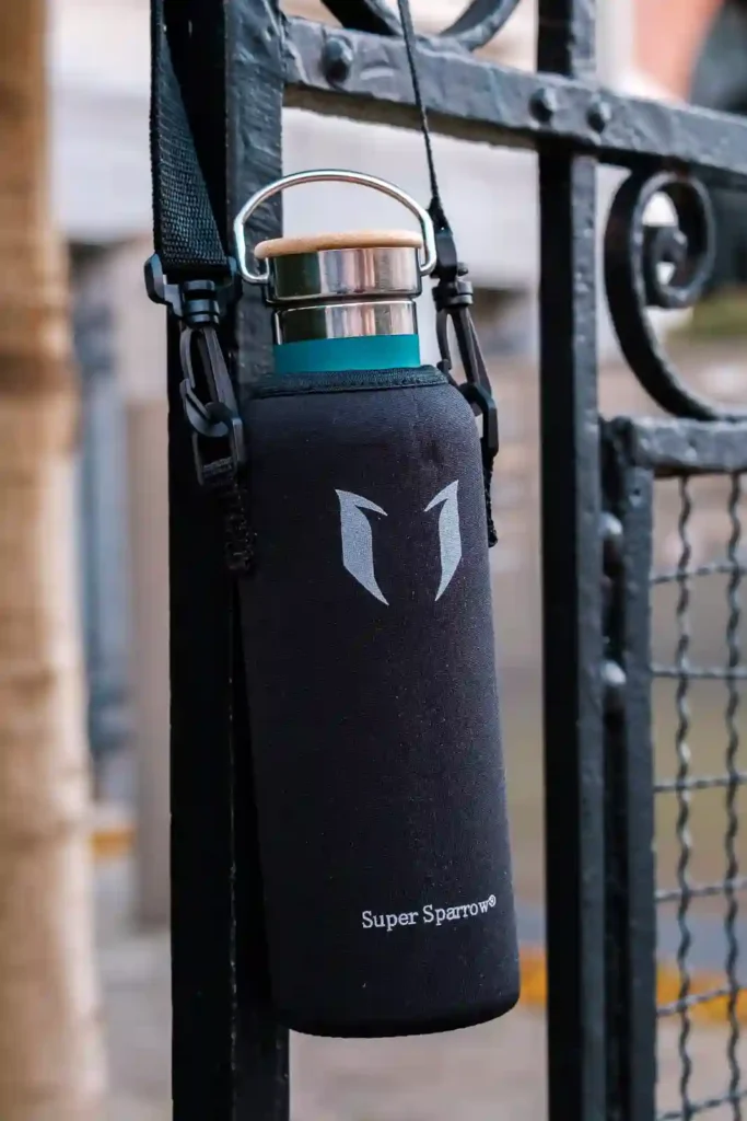 A green Super Sparrow bottle with a wooden and steel cap in its insulated sleeve accessory.