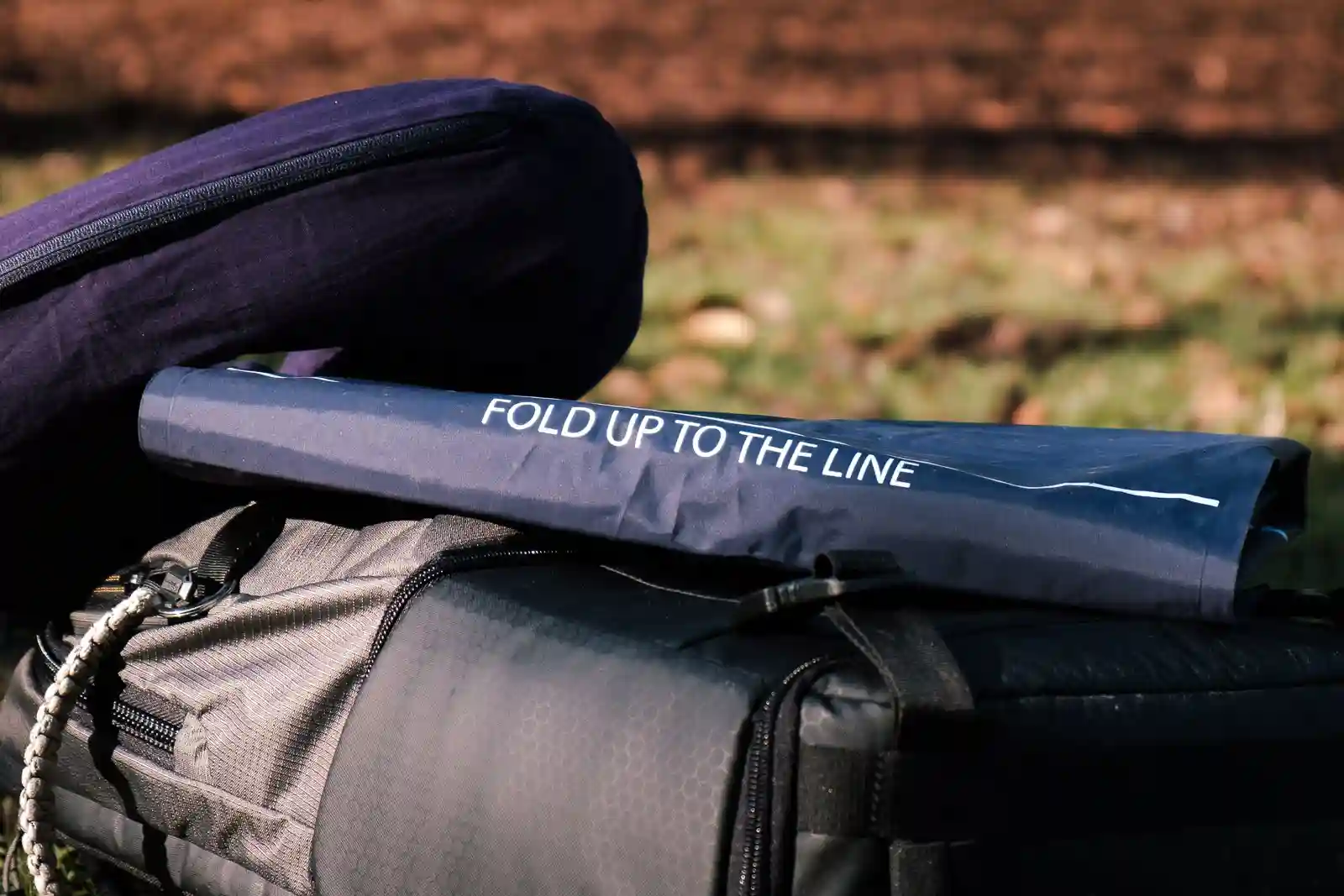 The rolled out LayOn Air Sleeping Pad next to a medium sized backpack for size comparison.