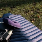 The rolled out LayOn Air Sleeping Pad next to a medium sized backpack for size comparison.