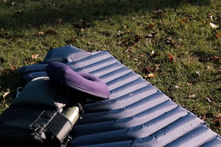 The rolled out LayOn Air Sleeping Pad next to a medium sized backpack for size comparison.