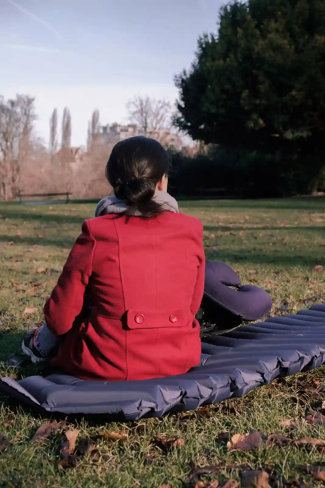 Ana from the Wildest Road sitting LayOn Air Sleeping Pad in a park.