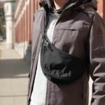 Luca from The Wildest Road wearing a black Uniqlo mini shoulder bag with a carabineer attached to the zipper.