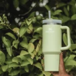 Light green Stanley cup quencher flowstate water bottle held up.