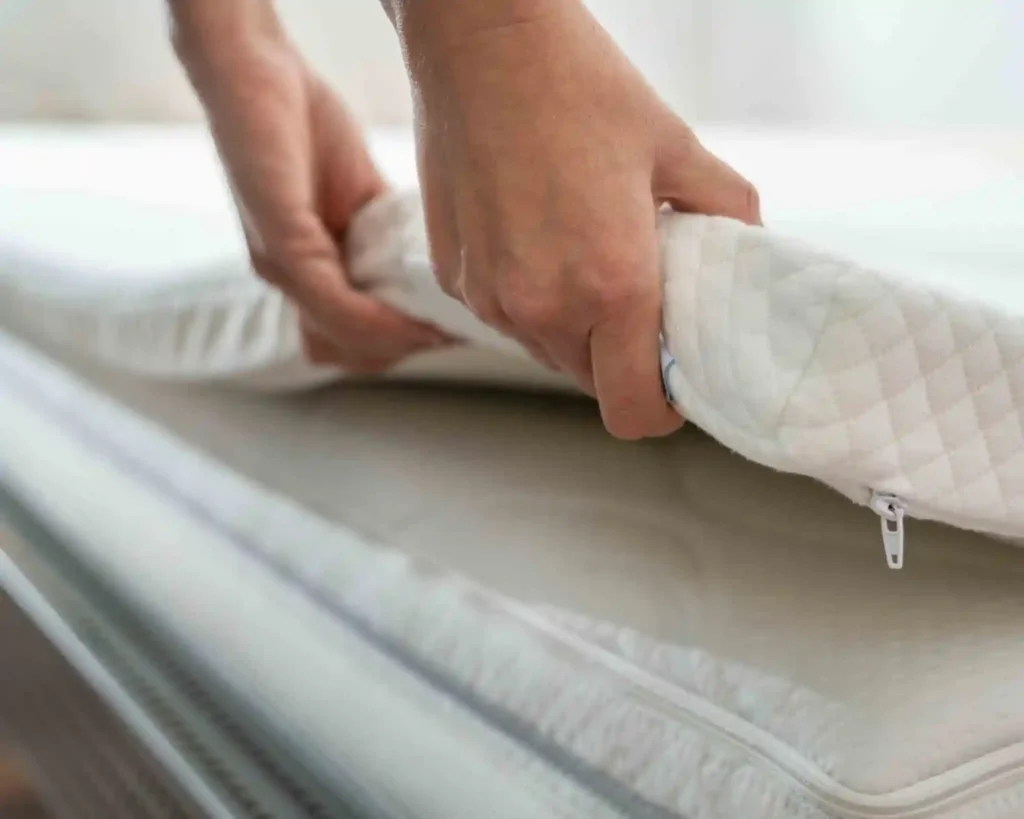 A person lifts a mattress from the bed frame.