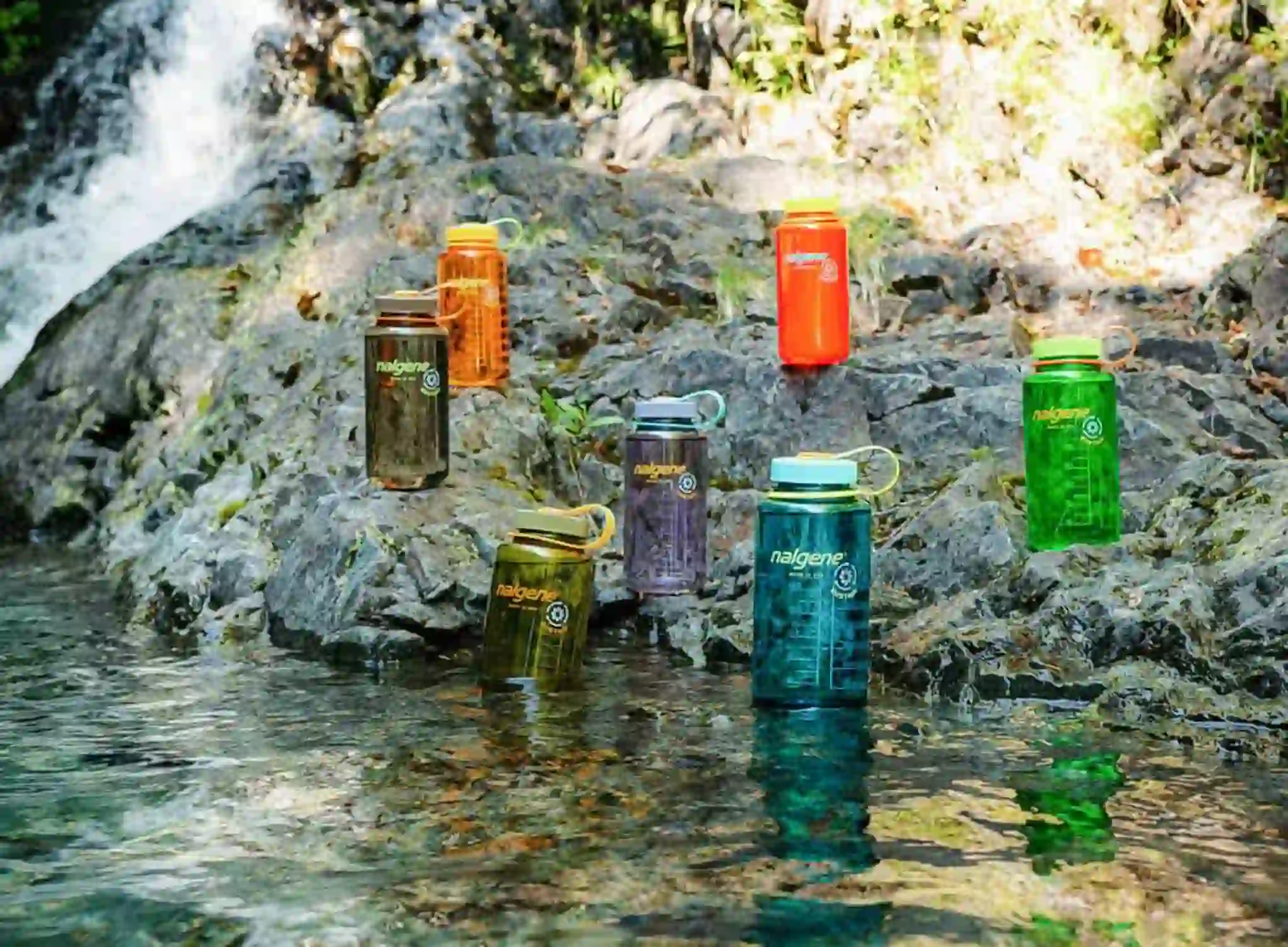 Nalgene sustainable water bottles outdoors in multiple colours.