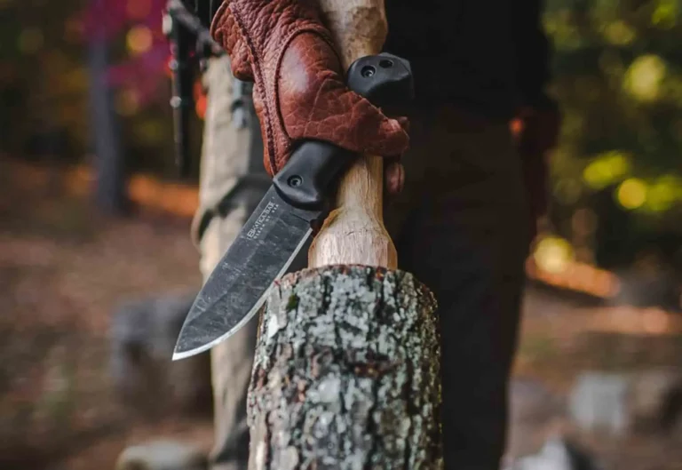 A Becker BK2 Campanion knife being used to remove bark from a large tree branch.