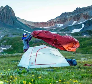 A camper setting up a Big Agnes tent in the mountains.