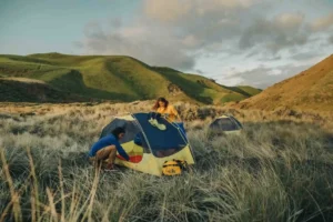 A North Face tent in a grassy plain, with mountains visible in the background.