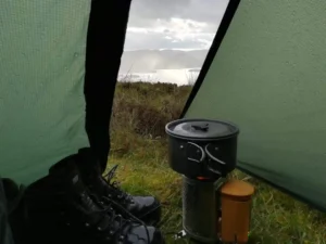 Mountain views from inside a camping tent with a cooking pot.